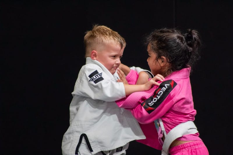 A boy and girl grip fighting during a partner drill