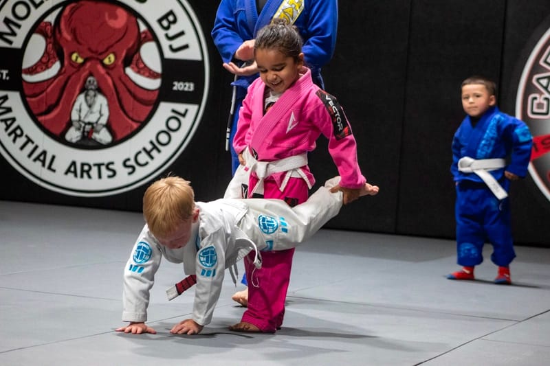 A little girl finishing a single-leg takedown on a partner