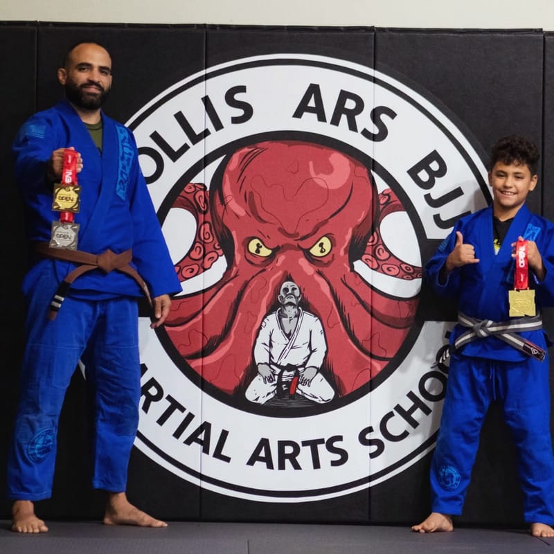 A student and coach with competition medals in front of the academy logo