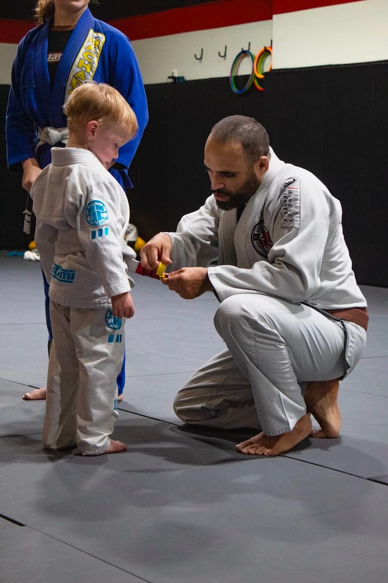 A small toddler receiving a belt promotion
